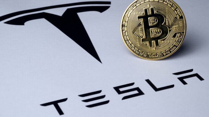 Tesla reclaims $1B in Bitcoin holdings even as shares fall Bild eines Bitcoins auf einer Papieroberfläche mit dem Tesla-Logo